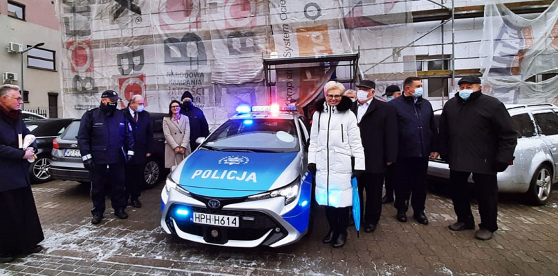 Nowy radiowóz i goście wydarzenia przekazania pojazdu na tle remontowanej siedziby płońskiej komendy policji [Fot. Łukasz Wielechowski]